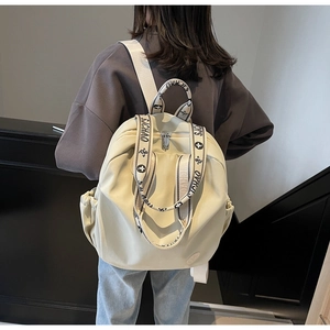 Rear view of model wearing a cream nylon backpack with branded SJCHAO woven straps
