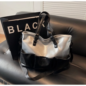Detail of silver metallic tote bag with black pockets and OFFBETTER logo on a leather sofa