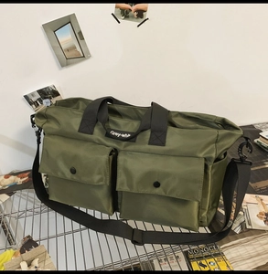 Macro detail of army green nylon travel tote with tactical cargo pockets and metal snaps