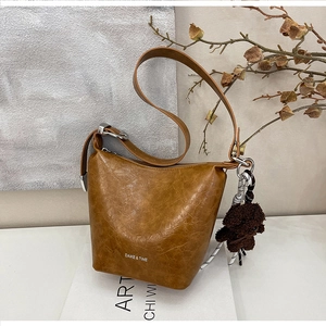 Detail of caramel bucket bag with leather texture and cute teddy bear charm pendant