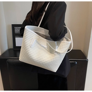 Side view of white woven tote bag with leather straps on a model in minimalist studio