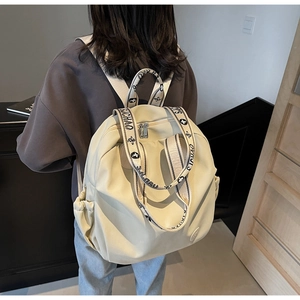 Close-up of the beige nylon backpack featuring stylish black and white jacquard straps