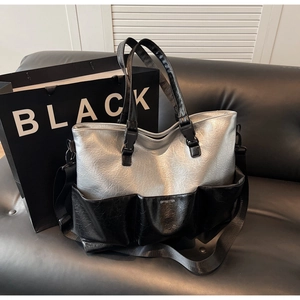 Detail of silver and black tote bag featuring outer pockets and a wide shoulder strap