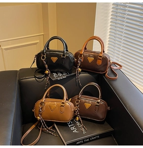 Close-up of leather cylinder bags with vintage gold hardware and woven knot charm