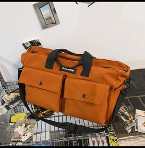 Detail of orange canvas tote bag with dual front flap pockets and branded strap