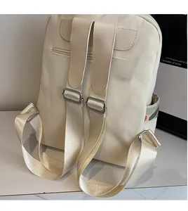 Detail of cream travel backpack showing wide adjustable straps and a hidden zipper back pocket