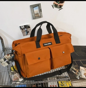 Detail of orange canvas tote bag featuring front flap pockets and black nylon straps