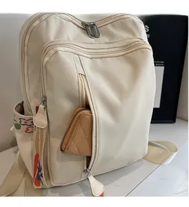 Detail of front zipper pocket on beige nylon backpack showing storage capacity for wallets