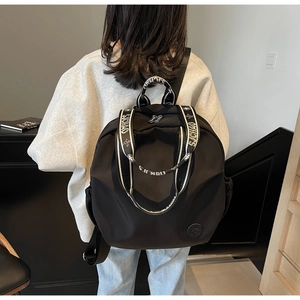 Detail of waterproof nylon backpack with white lettered straps on model back