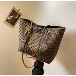 Detail of olive woven tote bag showing intricate cross-weave texture and slim leather straps