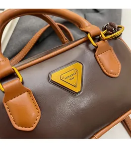 Close-up of brown synthetic leather Boston bag with triangle logo and fine stitching