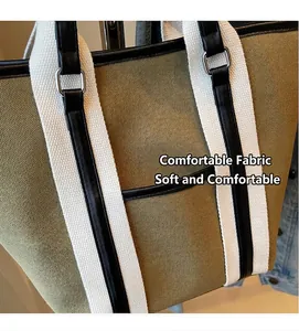 Macro detail of high-density olive canvas tote with striped strap and leather trim