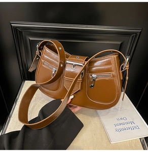 Detail of vintage brown crescent bag showing glossy leather texture and silver buckle