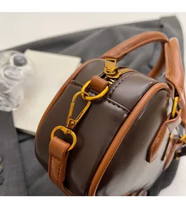 Close-up of brown leather pillow bag featuring fine texture and gold metal zipper hardware