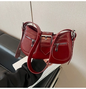 Detail of burgundy vintage underarm bag with glossy leather texture and tassel zipper