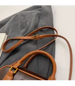 Close-up of brown leather bag with adjustable shoulder strap and gold hardware