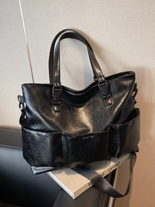 Large black textured leather tote bag with multi-pocket design and wide shoulder strap