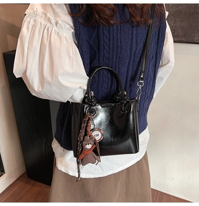 Detalle de bolso tipo cubo negro brillante con colgante de oso y accesorio Las Vegas