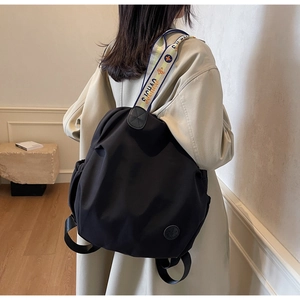 Detail of black nylon backpack featuring a wide colorful jacquard strap and brand logo