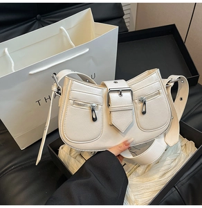 Detail of cream white cracked leather bag with silver buckles and zipper pockets