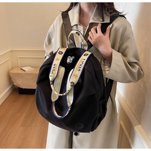 Detail of black nylon backpack featuring contrast floral print handles and side pockets