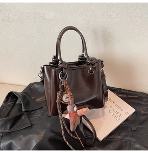 Détail du sac seau en cuir ciré marron foncé avec pendentif ours mignon