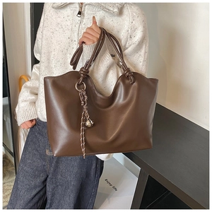Detail of dark brown tote bag with wavy opening and elegant knot tassel detail