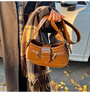 Close-up of brown vintage leather shoulder bag with white stitching and zipper details