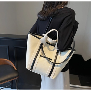 Detail view of large beige canvas tote bag with black leather trim and dual straps
