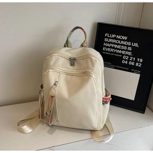 Close-up of beige nylon backpack with ethnic style woven ribbons on front zipper pockets