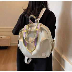 Detail of cream nylon backpack with colorful S.JCHAO woven handle and side pocket