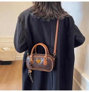 Detail of vintage brown boston bag with contrast handles and triangle metal hardware