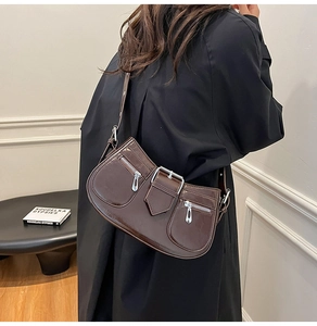 Detail view of glossy dark brown crescent bag with silver buckles and zipper accents