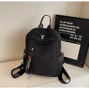 Detail of black backpack featuring ethnic embroidery straps and multi-pocket design