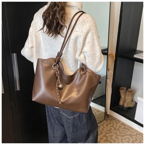 Close-up of brown tote bag showing wave-edge design and knot shoulder strap detail