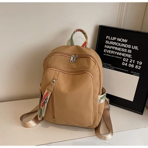 Macro detail of khaki travel backpack with colorful ethnic style woven zipper pulls