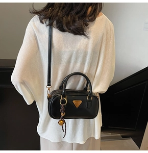 Detailed back view of a black leather pillow bag with gold triangle logo and strap