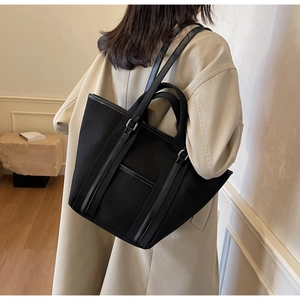 Close-up of black canvas tote bag with leather trim on model for office commute