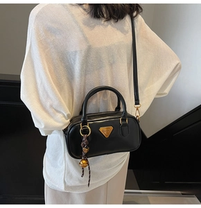 Detailed view of black matte leather Boston bag with triangle logo and decorative charm