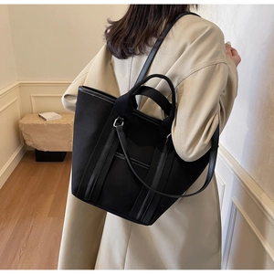 Model view showcasing the black canvas tote bag's large capacity and stylish carry options