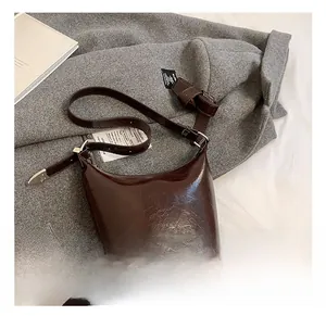 Detailed close-up of dark brown oily leather bucket bag with silver metal buckles