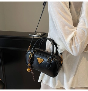 Detail of black Boston pillow bag featuring gold hardware and logo triangle plate
