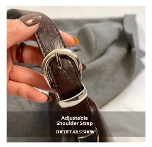 Detail of adjustable shoulder strap with silver buckle on dark brown leather bucket bag