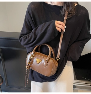 Detail of a brown Boston bag showing the textured leather and woven rope pendant
