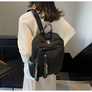 Detailed view of black nylon backpack featuring colorful striped webbing on top handle