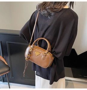 Close-up of brown leather Boston bag with gold triangle logo and striped silk scarf detail
