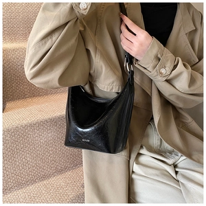 Detail of black wrinkled patent leather hobo bag featuring white NO FILTER lettering