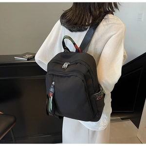 Detail of a black nylon backpack with colorful zippers and multiple storage compartments