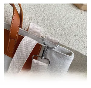 Detail of silver metal hook and durable brown leather handle on a canvas tote bag