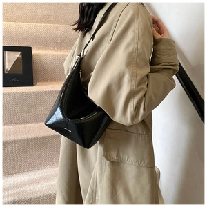 Detail of black glossy leather hobo bag with white NO FILTER slogan on a model